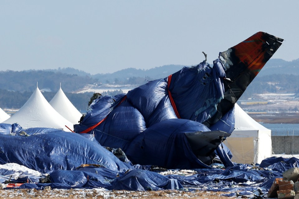 Debris of a crashed Jeju Air passenger plane covered in tarpaulins at Muan International Airport.