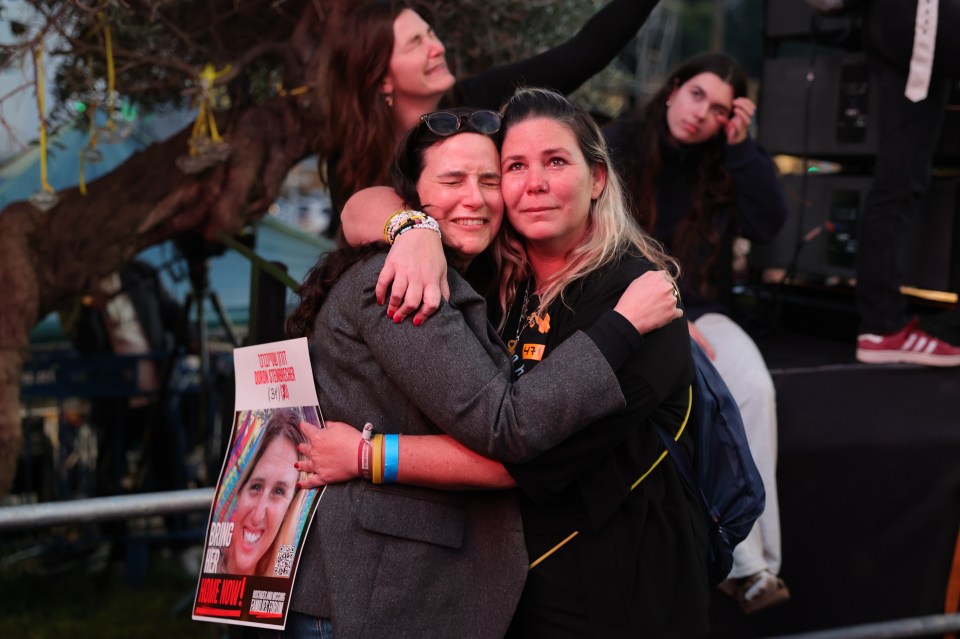 Two women embrace, one holding a photo of a released Israeli hostage.