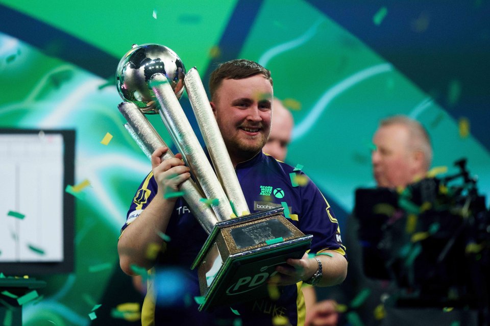 Luke Littler holding the Paddy Power World Darts Championship trophy.