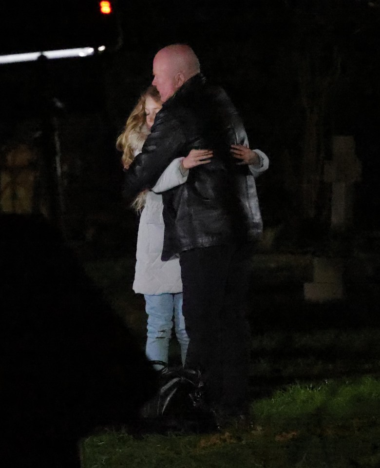 A man and woman embracing at night near graves.