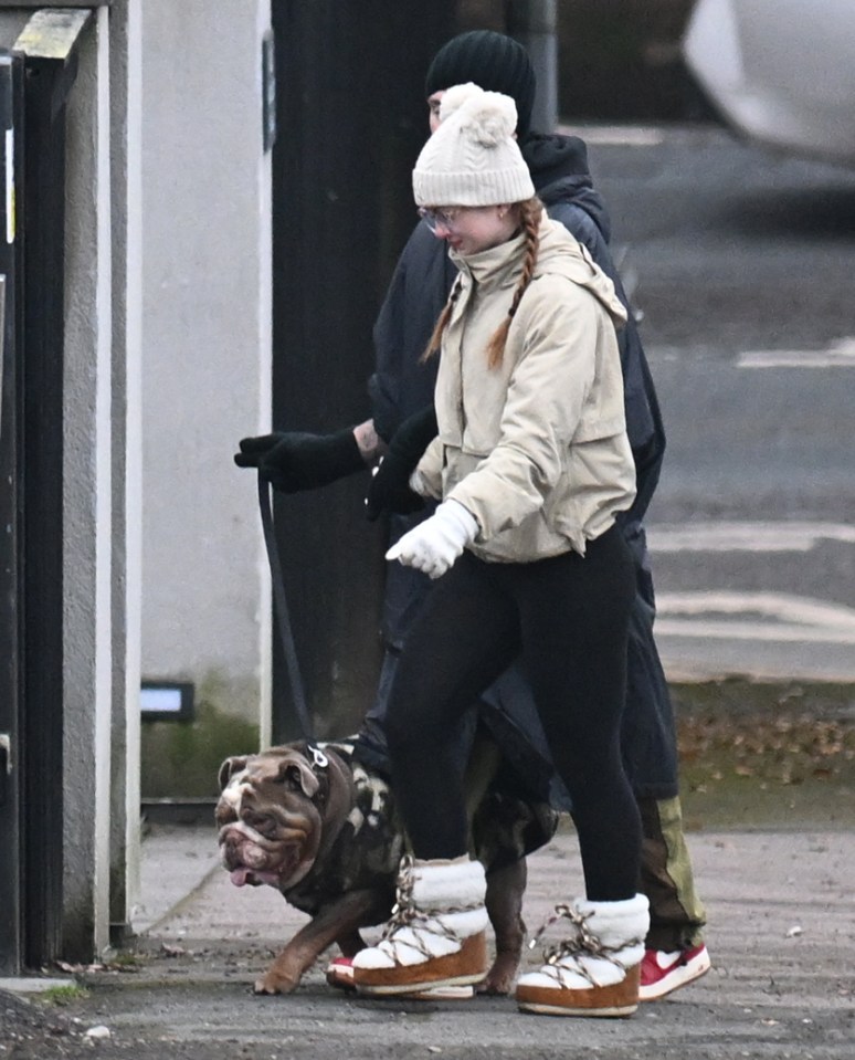 Woman walking a bulldog with a man.