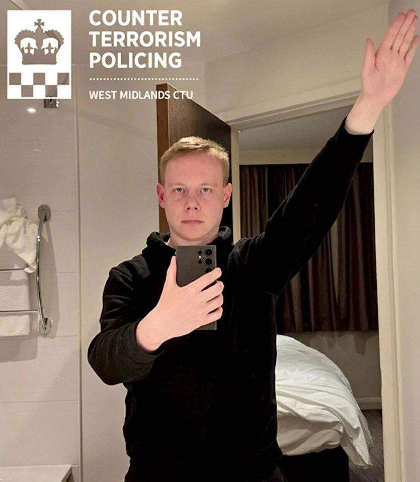 Man taking selfie in hotel bathroom, raising his right hand.  West Midlands Counter Terrorism Policing logo visible.