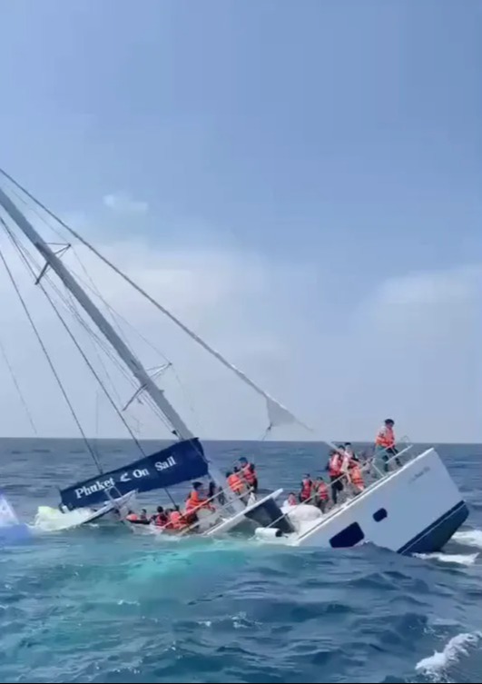 Catamaran sinking with passengers being rescued.