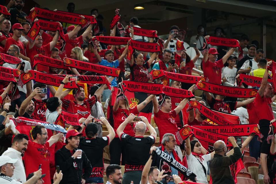 Mallorca fans holding up scarves before a soccer match.