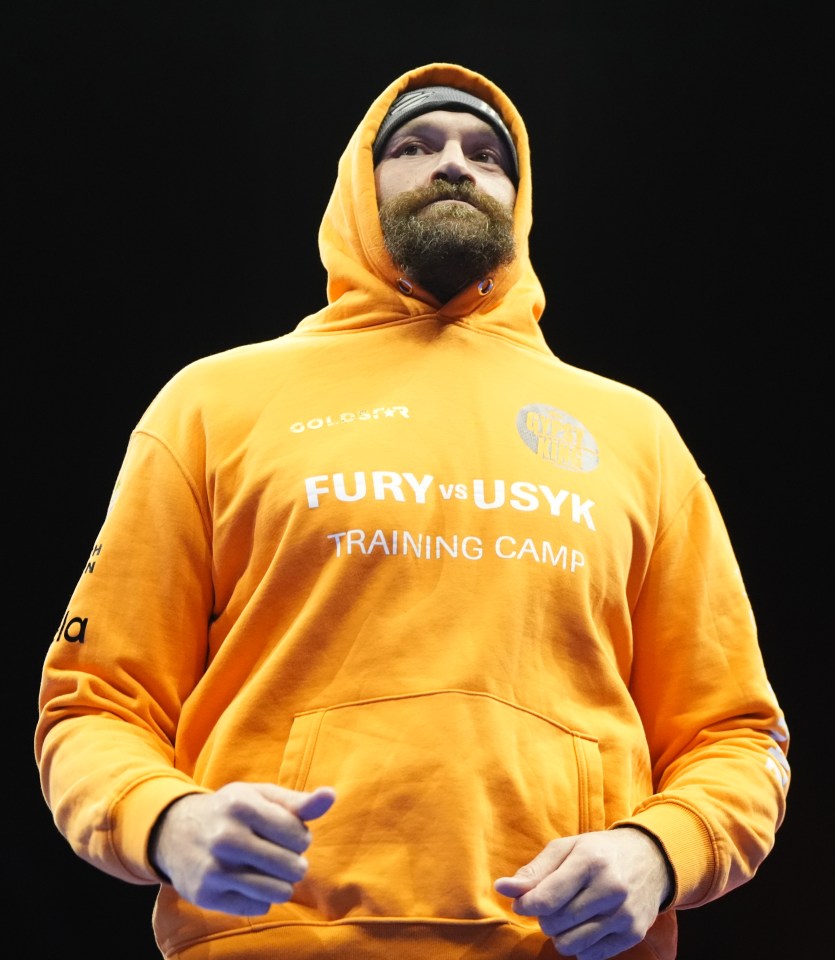 Tyson Fury in an orange hoodie that says "Fury vs Usyk Training Camp".