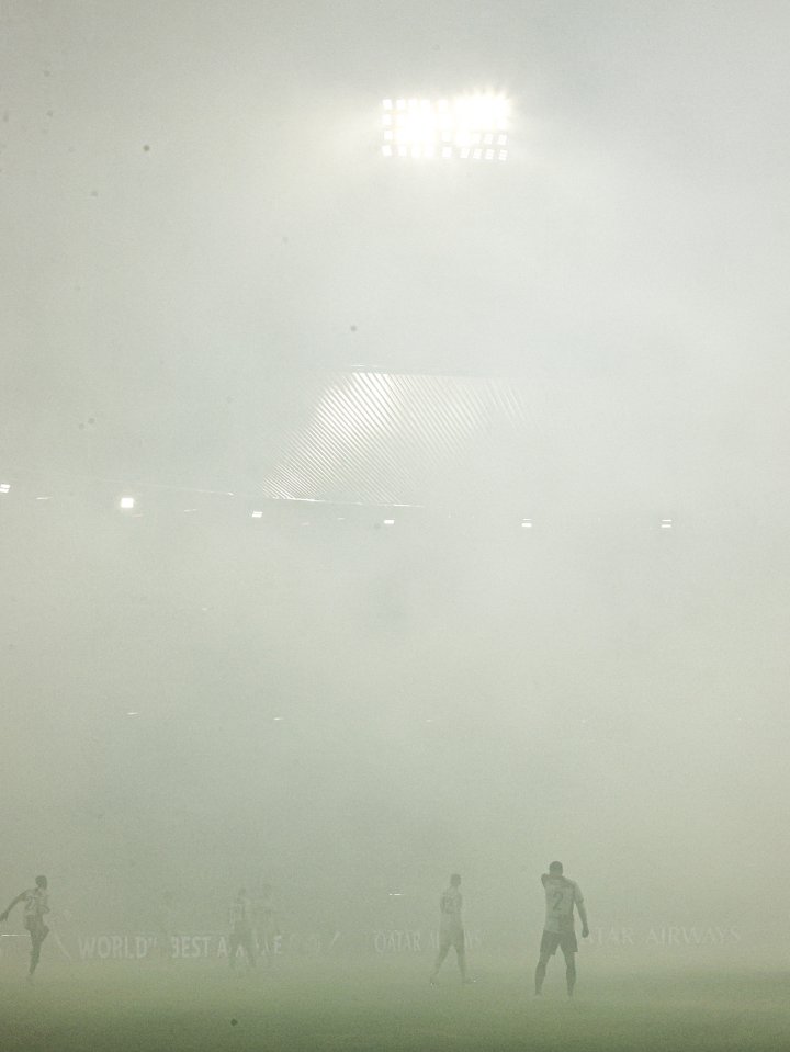 Soccer players on a foggy field.