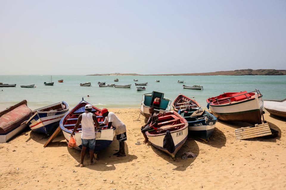 Fishermen with their boats on a sandy beach.