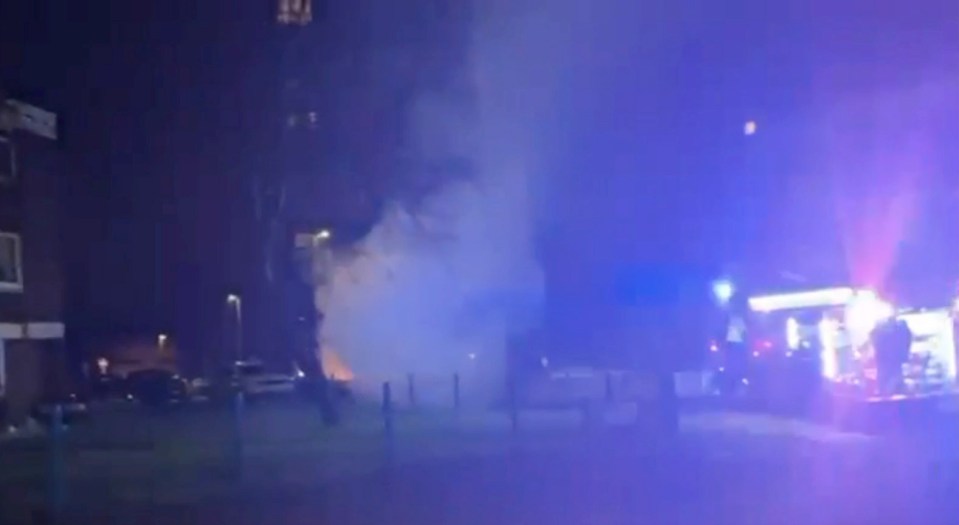 Firefighters battling a car fire at night.