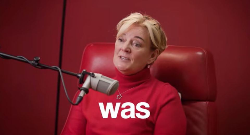 Woman in red speaking into a microphone.