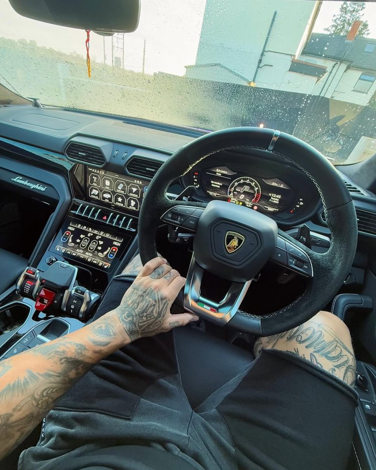 Person with tattoos driving a Lamborghini Urus.