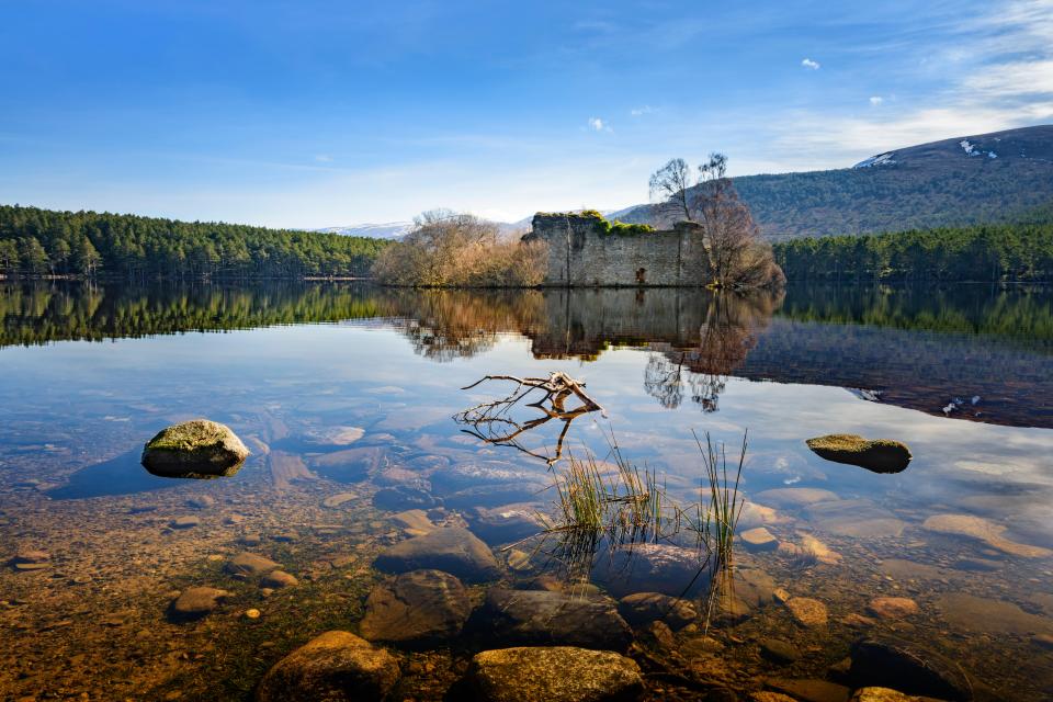 Loch an Eilein castle ruins reflected in a calm loch.