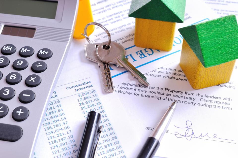 Mortgage loan agreement with calculator, keys, and house models.