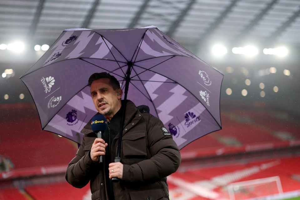 Gary Neville giving a television interview under an umbrella.