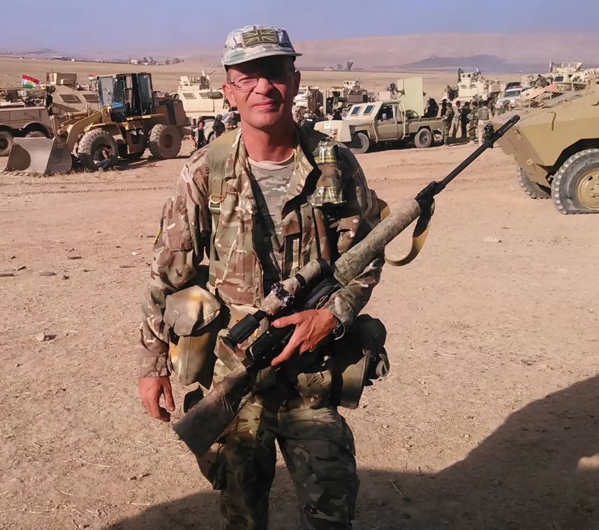 Soldier with rifle in a desert setting.