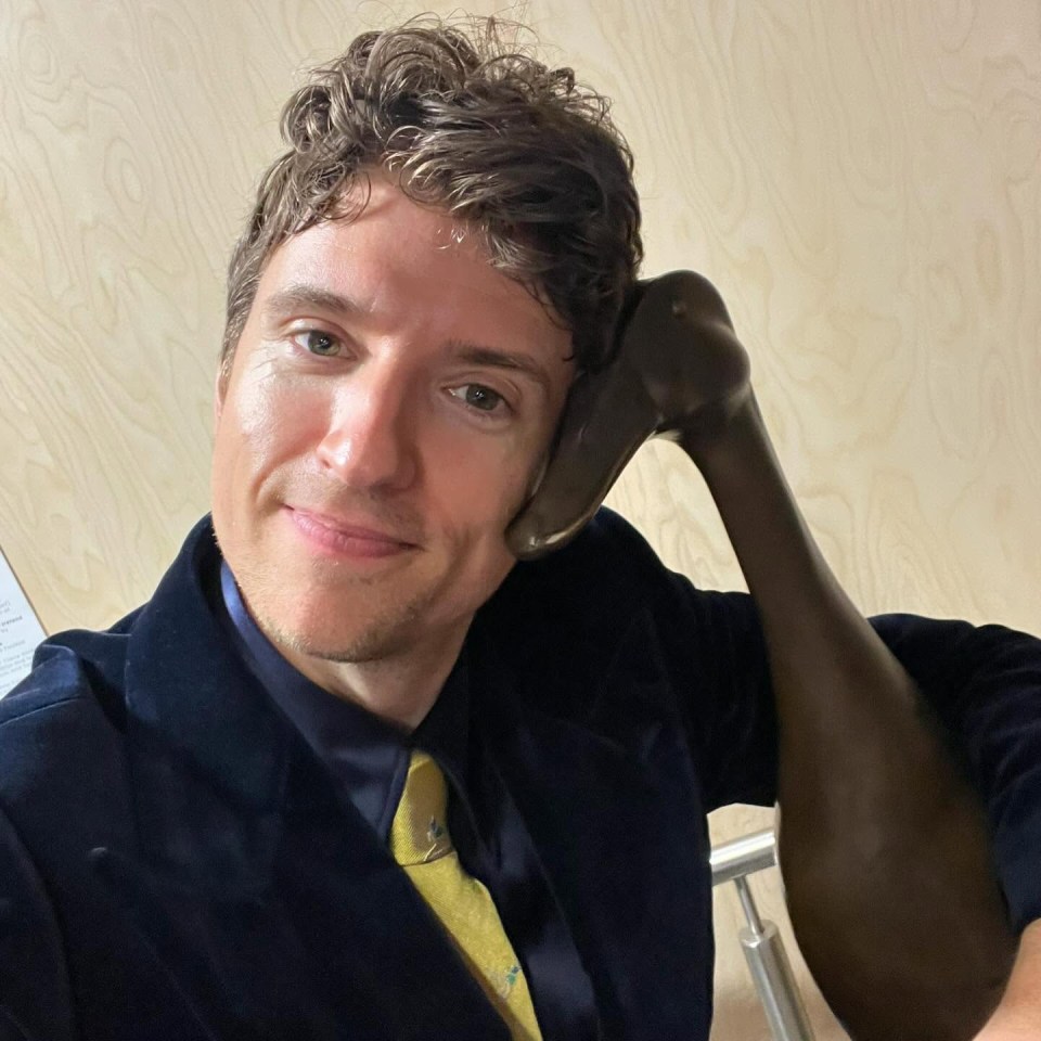 Greg James with a dark-colored sculpture resting on his shoulder.