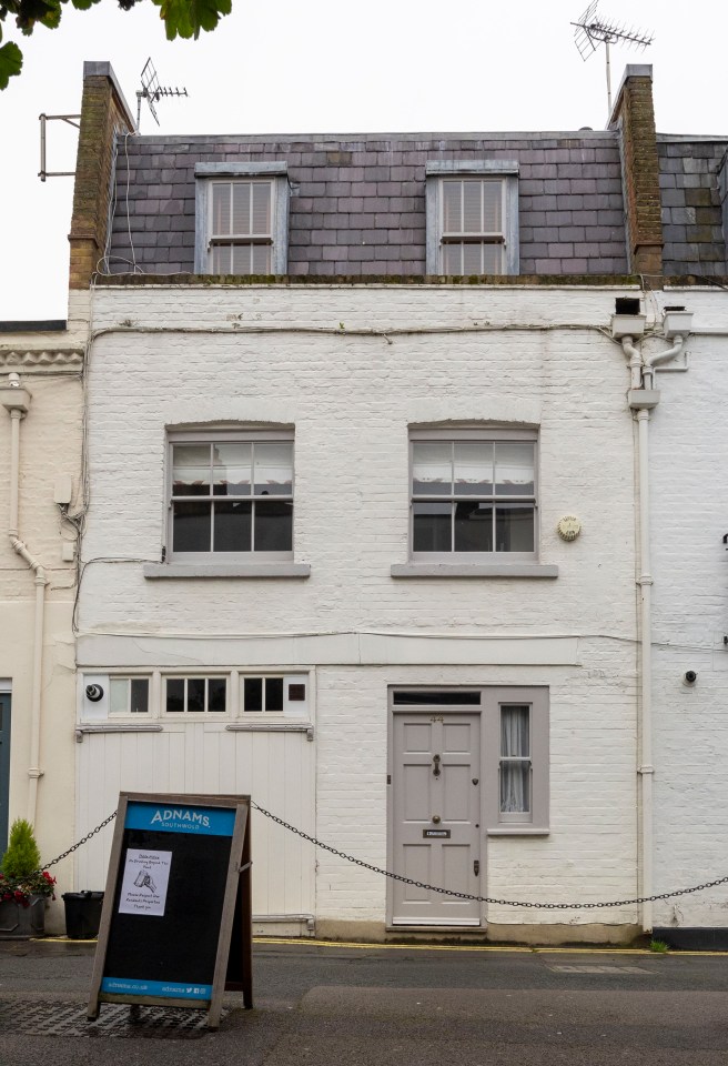 A white brick house in London with a gray door and a sign for Adnams Southwold.