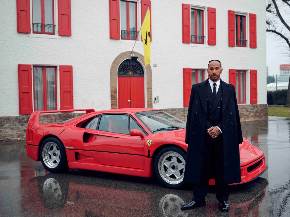 Lewis Hamilton standing by a red Ferrari.