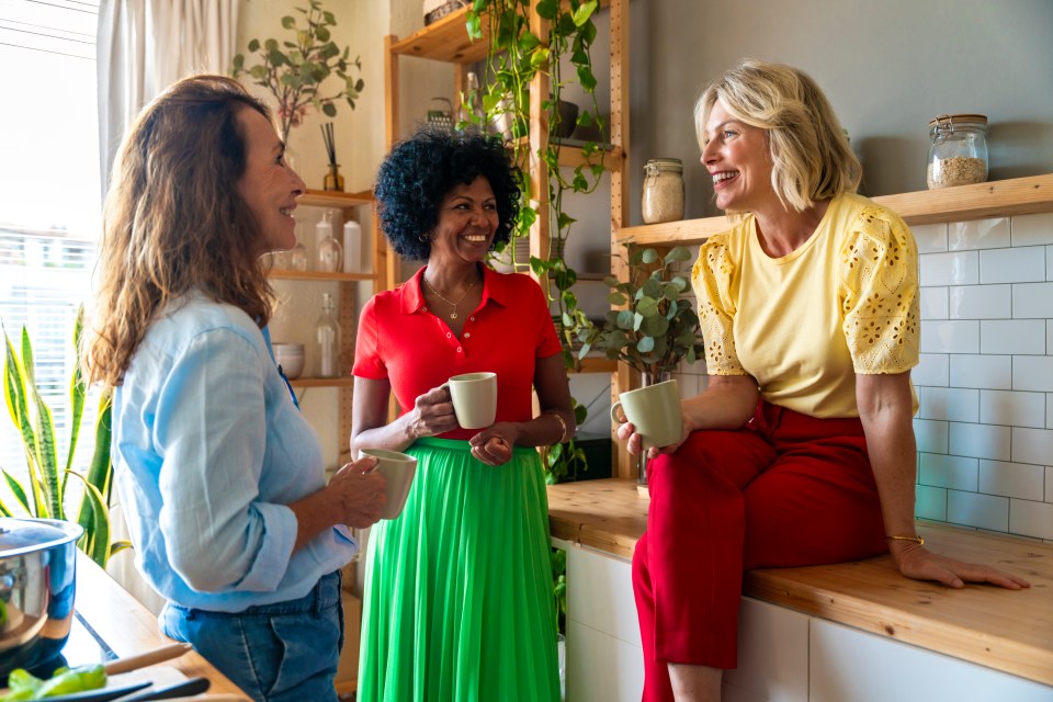 Three women enjoying coffee together in a kitchen.