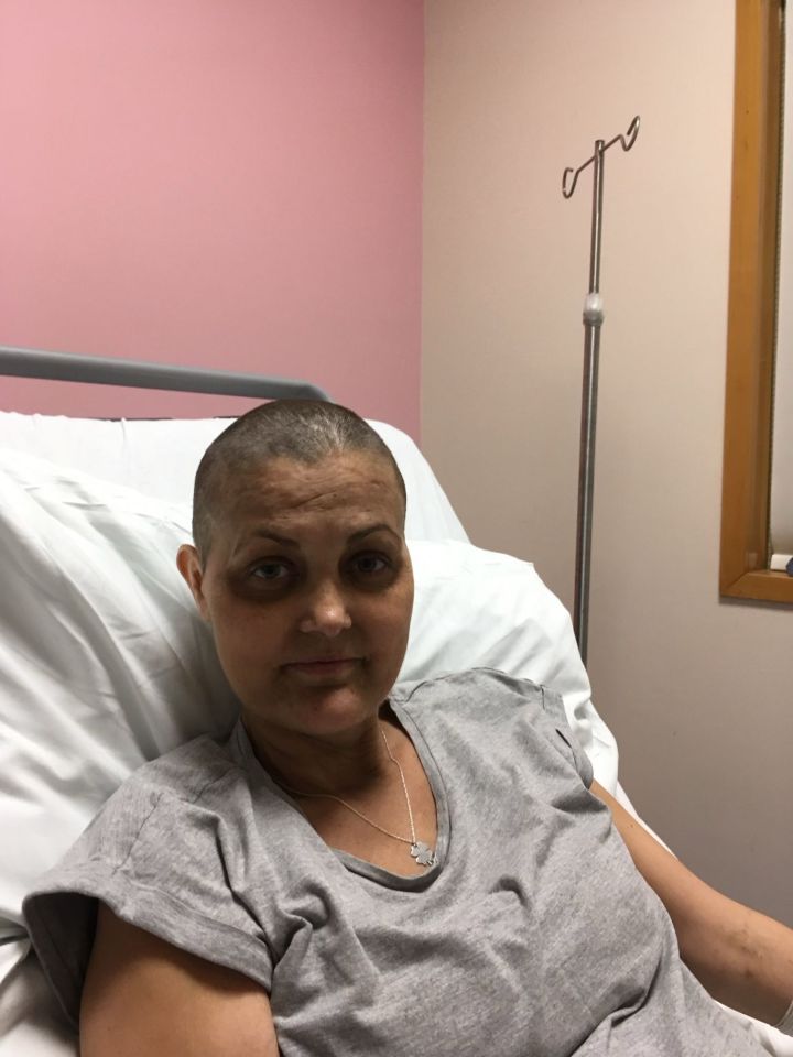 Woman with shaved head in hospital bed.