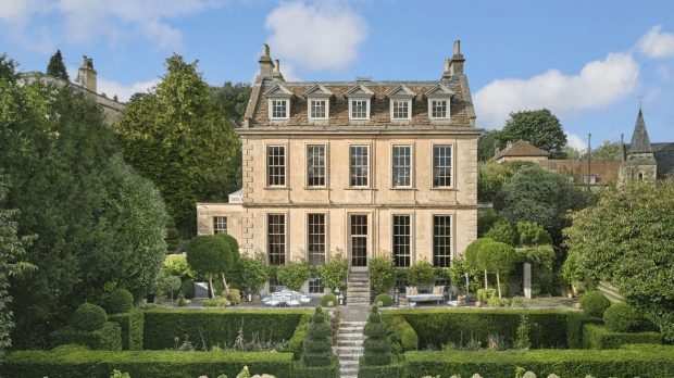 Large beige manor house with manicured gardens.