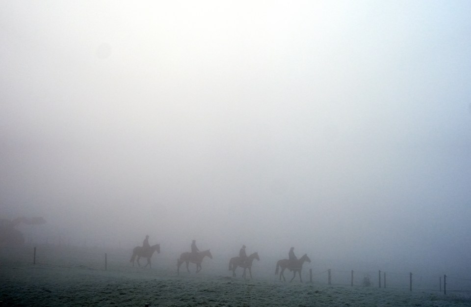 Four riders on horseback in thick fog.