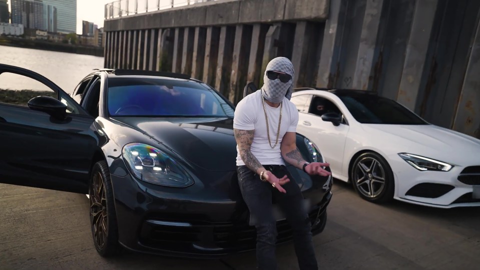 Man in a mask sitting on a car.