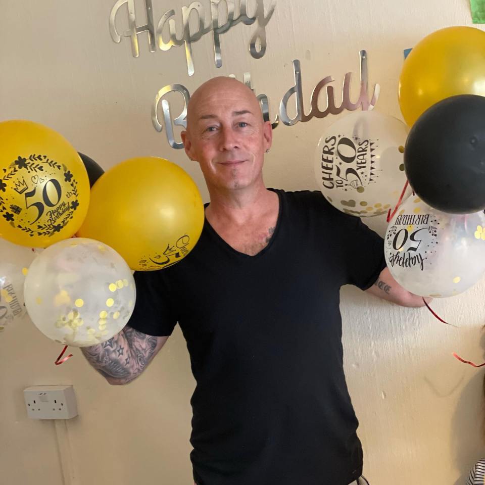 Man holding 50th birthday balloons.