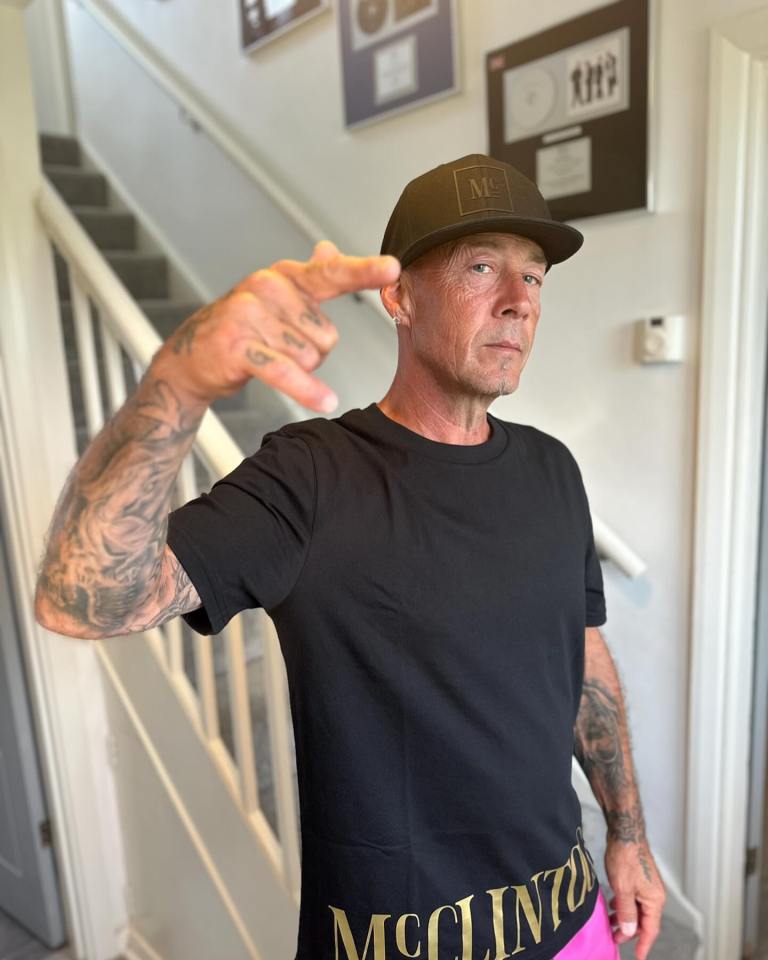 Man with tattoos making a hand gesture.