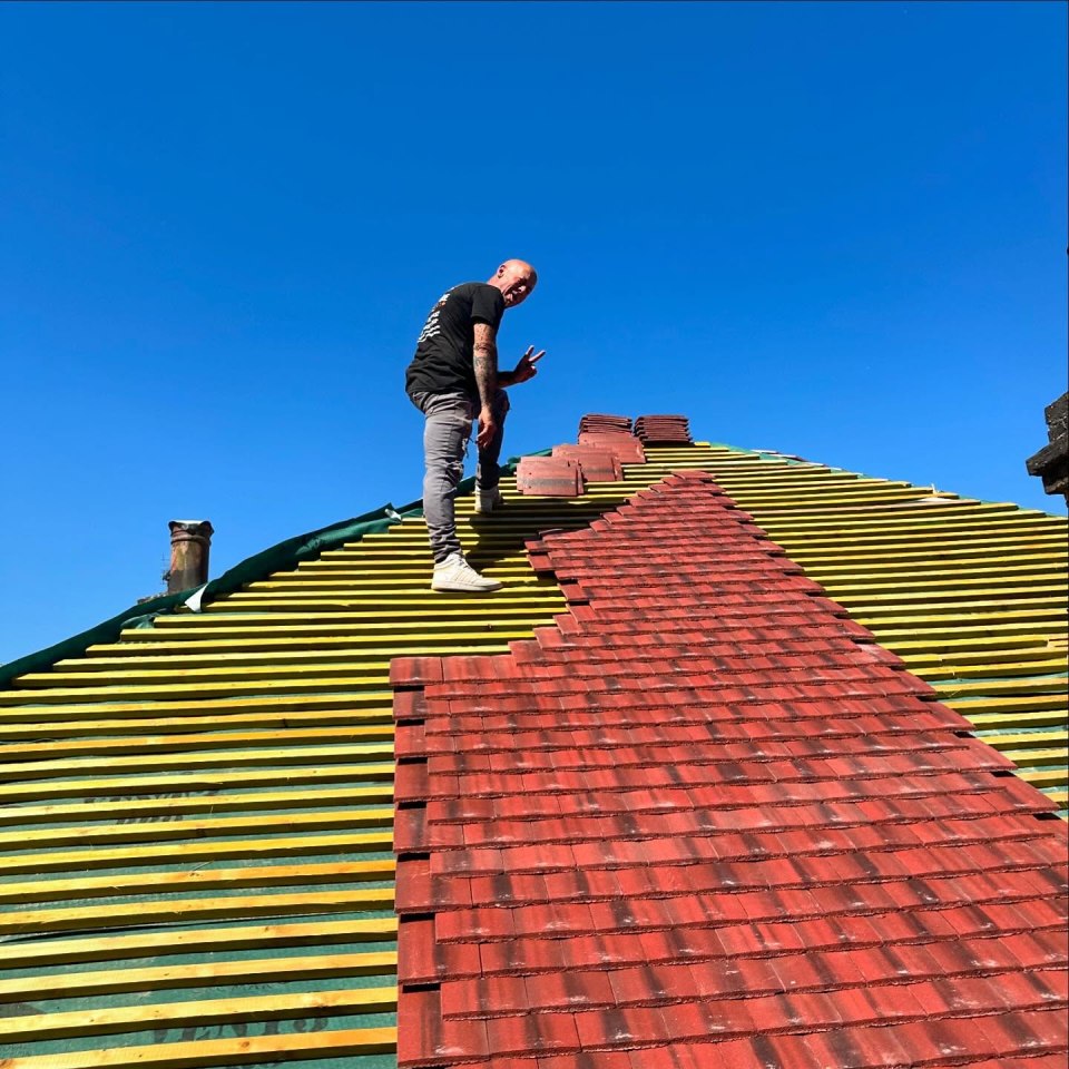 Man installing red roof tiles.