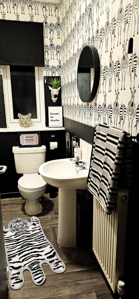 Bathroom with zebra-print wallpaper, rug, and towels.