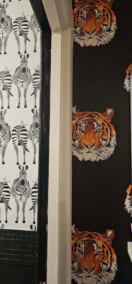 Illustration of a bathroom with zebra and tiger patterned wallpaper.