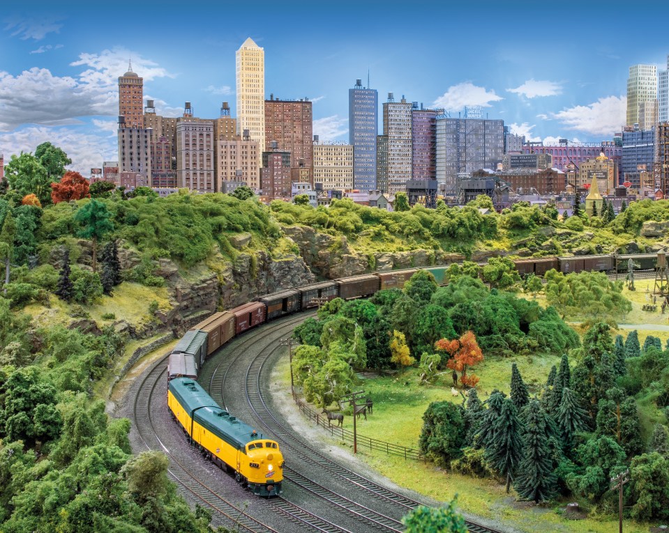 Model train layout with a city skyline in the background.