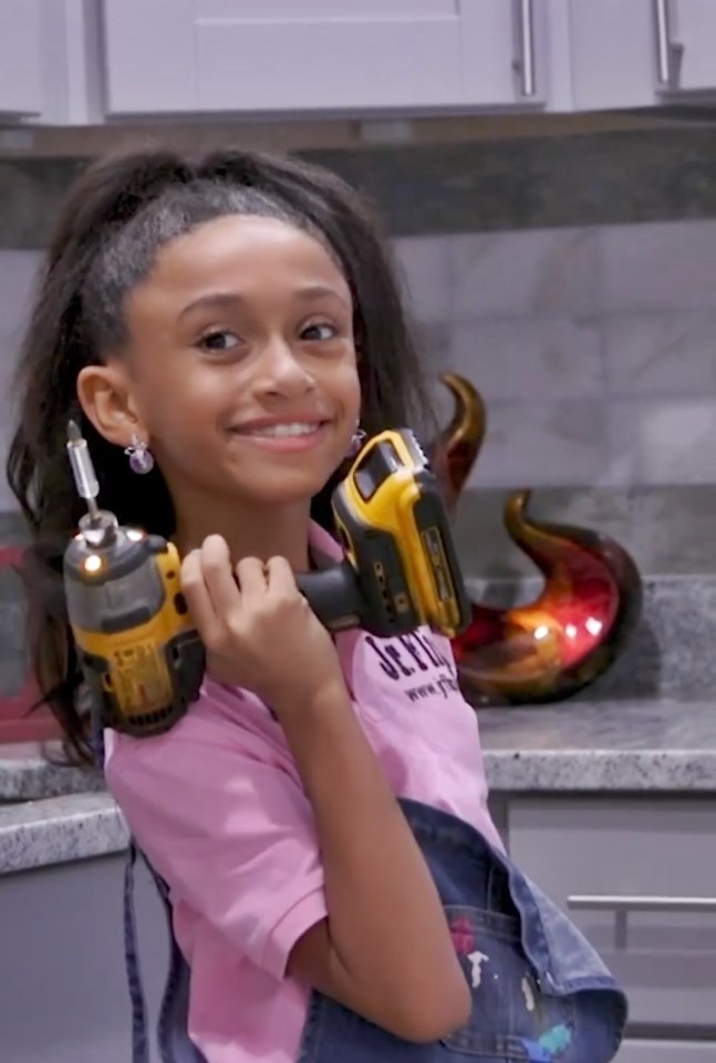 A teenage girl holds two power drills.