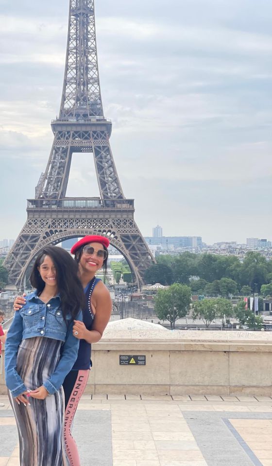 A mother and daughter pose in front of the Eiffel Tower.