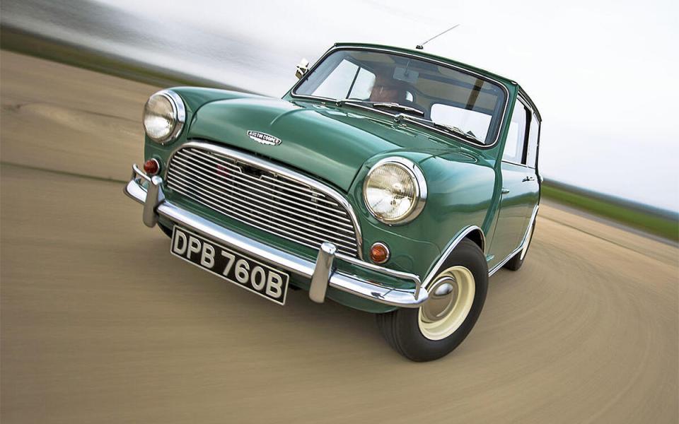 Green Austin Mini Cooper driving on a road.