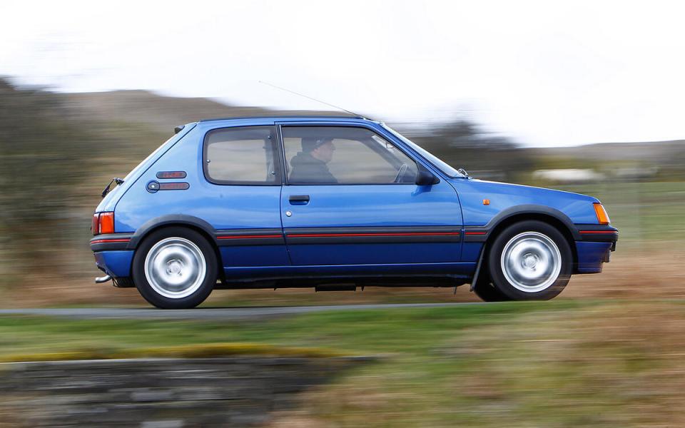 Blue Peugeot 106 Rallye driving on a road.