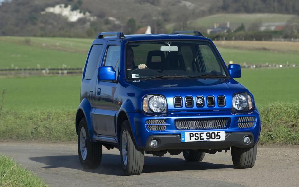 Blue Suzuki Jimny driving on a country road.