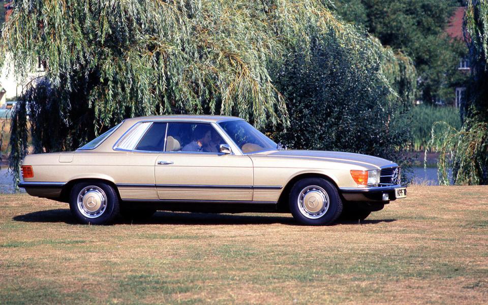 Beige Mercedes-Benz 450 SLC coupe parked on a grassy area.