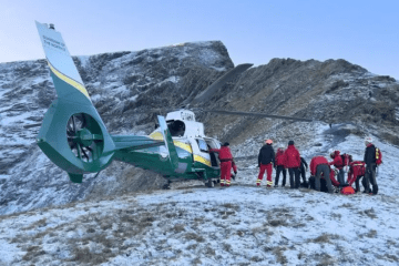 Mountain rescue team attending to a casualty near a helicopter.