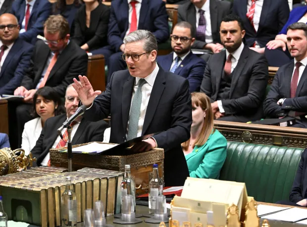 A man speaking at a podium in a parliament chamber.