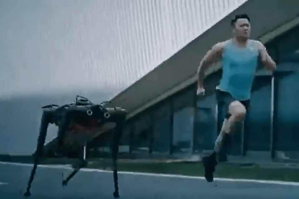 Man running alongside a robotic quadruped.