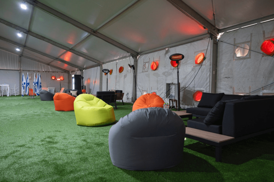 Lounge area with beanbag chairs and a sofa in a tent.