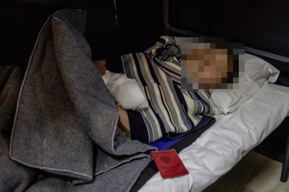 Person with bandaged hand lying in bed, passport visible.