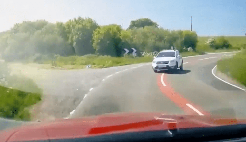 White car navigating a bend in the road.