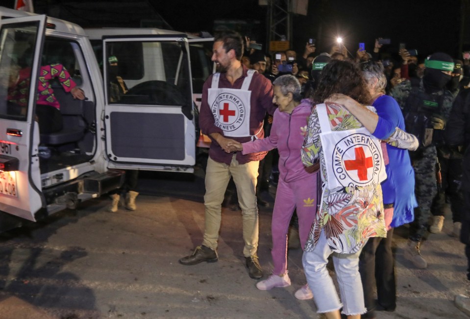 People embracing near a Red Cross vehicle.