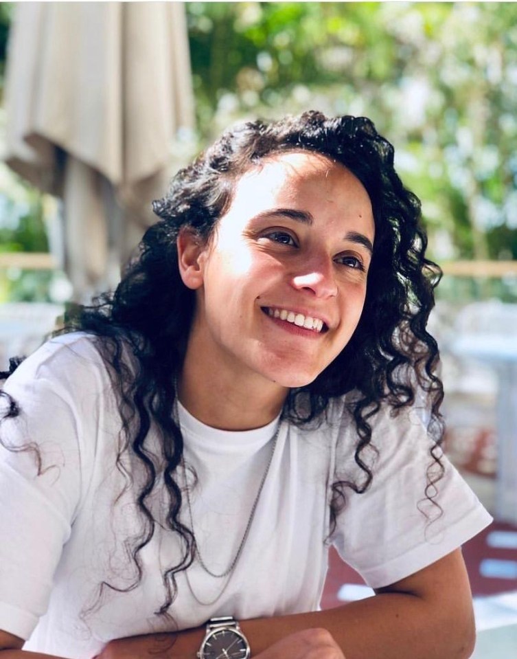 Woman with curly hair smiling outdoors.