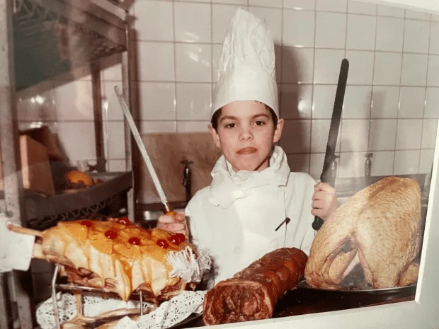 Young chef with roasted meats and pastries.