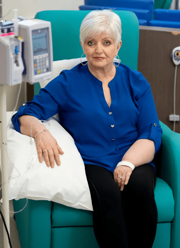 Woman in blue shirt receiving intravenous treatment.