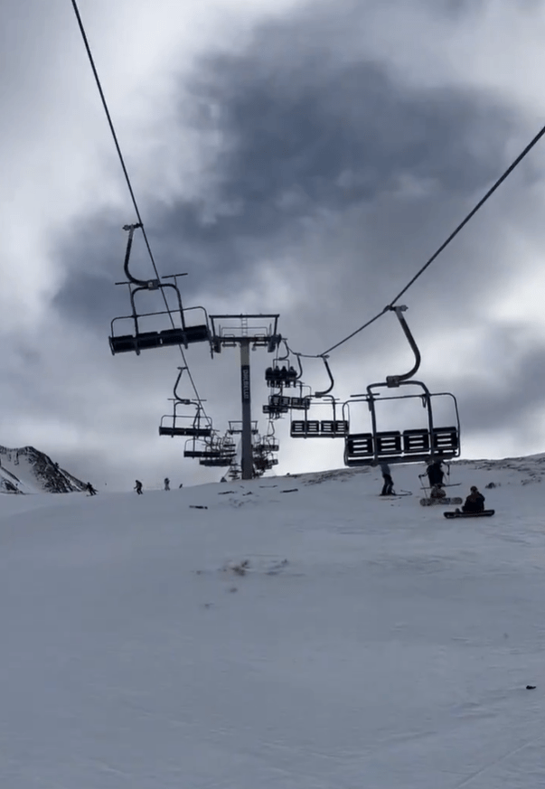 Ski lift chairs ascending a snowy mountain.