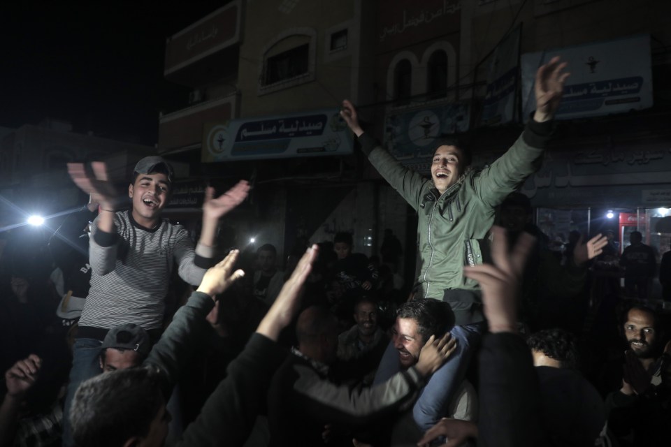 A man is being carried on the shoulders of a crowd of people at night.